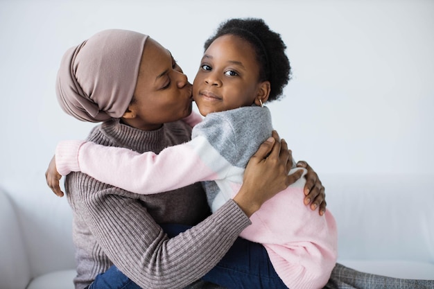 Woman embracing and kissing her daughter on couch