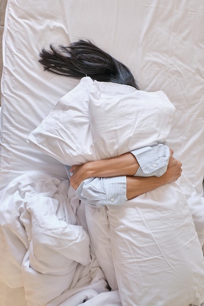 Woman embracing pillows and sleeping in bed