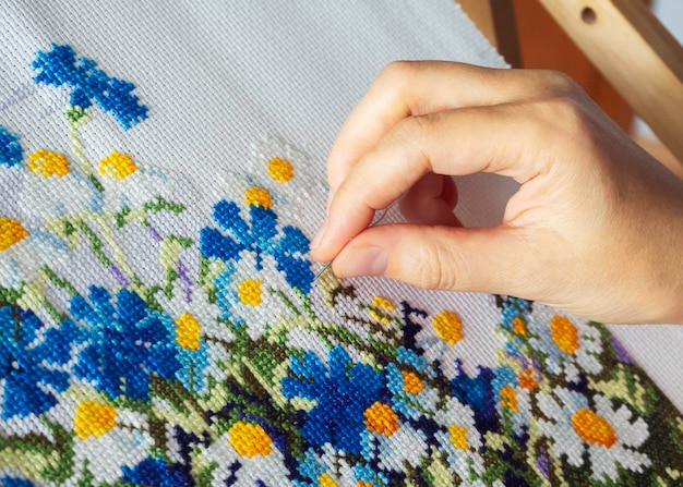 woman embroidering a floral pattern by hand with a needle