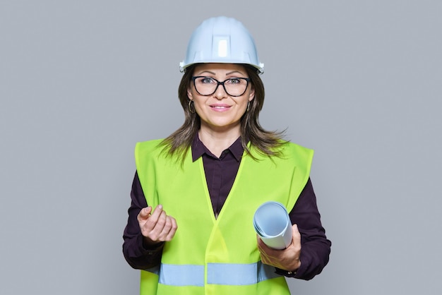 Woman engineer architect in helmet protective vest on grey background