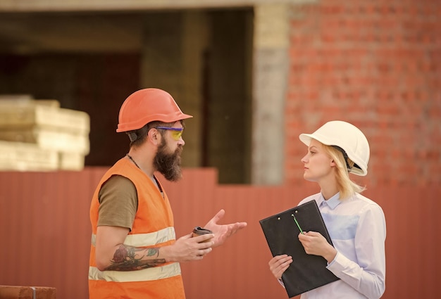 Woman engineer and bearded brutal builder discuss construction progress relationships construction client and participant building industry discuss progress plan construction industry concept