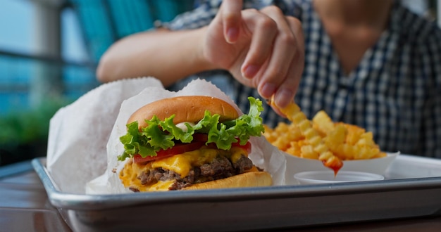 女性はハンバーガーとフライド ポテトを楽しむ