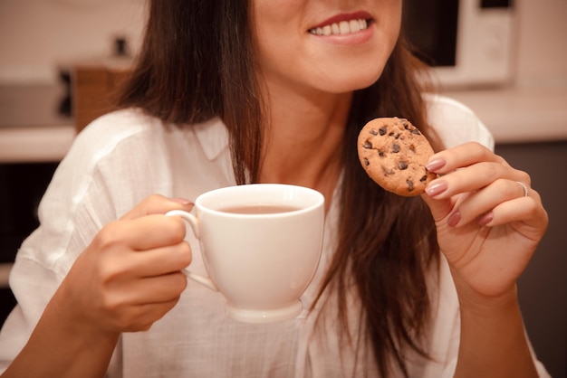 Photo woman enjoy coffee break with crisp cookie with chocolate chip in kitchen at home