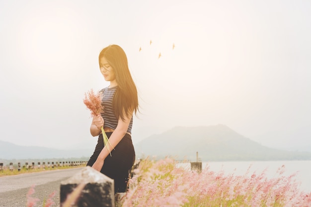 Woman enjoy grass flower in meadow at sunset