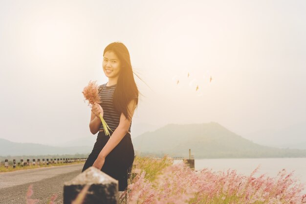 Женщина пользуется травой цветок на лугу на закате