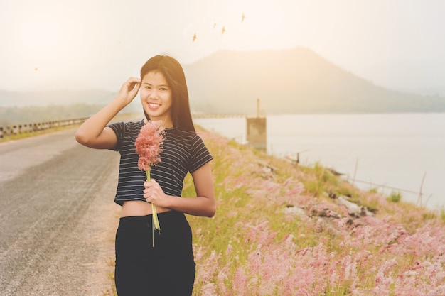 Woman enjoy grass flower in meadow at sunset