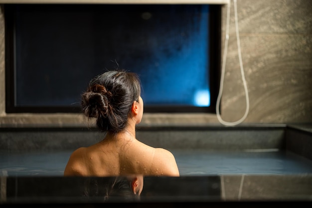 女性はリゾートで浴槽でオンセンを楽しんでいます
