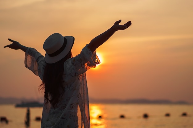 女性、夕暮れの海のビーチで楽しむ