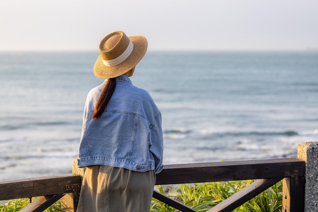 女性は日没時に海の景色を楽しんでいます