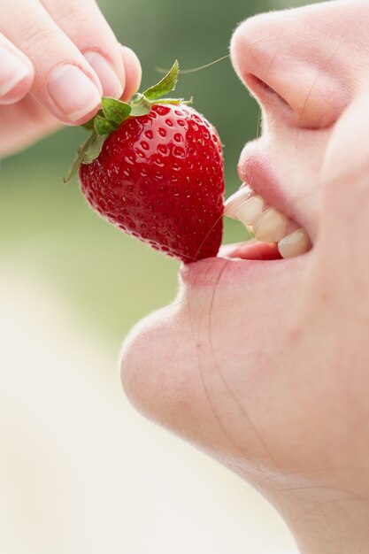 Woman enjoy strawberry on blurred green background