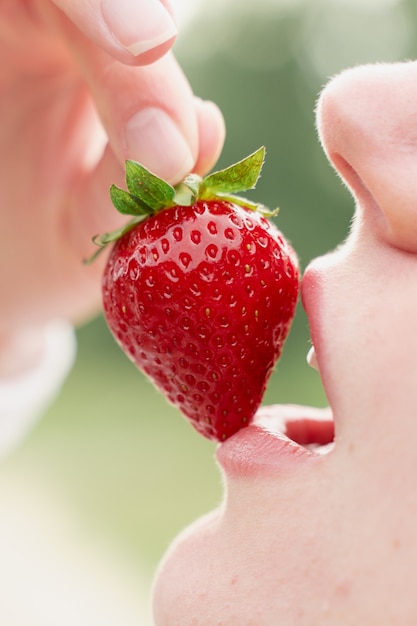 Woman enjoy strawberry closeup. Kisses and tastes strawberry. Seasonal berry.