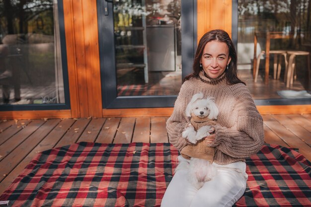 Woman enjoying in autumn day with white puppy outdoors