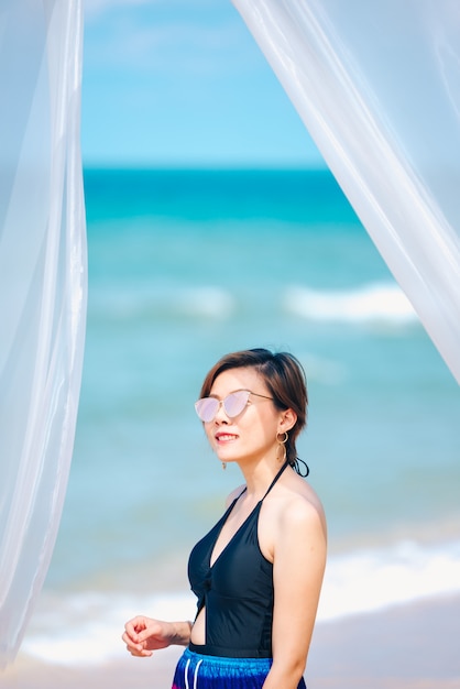 Woman enjoying beach relaxing joyful in summer by tropical blue water. 