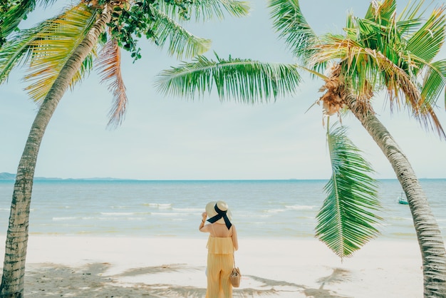 Donna che gode del rilassamento della spiaggia allegro di estate dall'acqua blu tropicale.