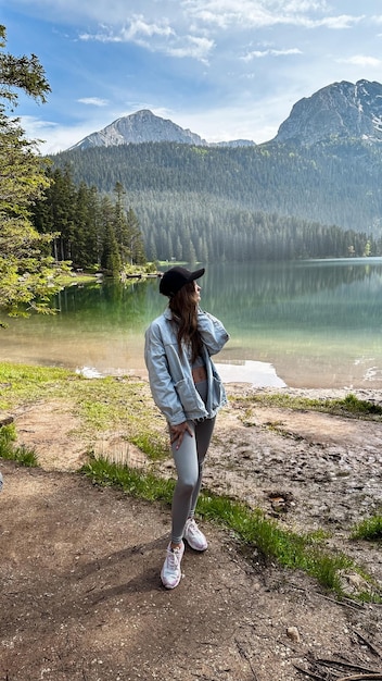 Foto donna che gode della bellezza della natura guardando il lago di montagna in montenegro