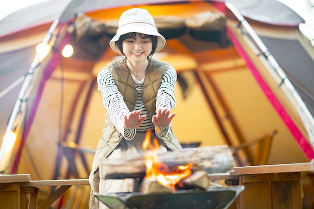 A woman enjoying a bonfire in front of tent