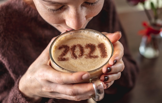 Woman enjoying a coffee with 2021 on the cinnamon milk foam