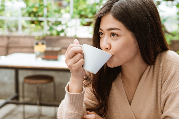 Woman enjoying drinking coffee in cafe