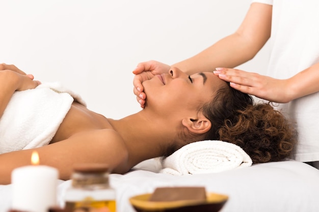 Woman enjoying face massage in spa salon