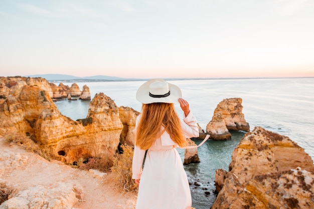 Woman enjoying great view on the rocky coastline during the sunrise in Lagos on the south of Portugal