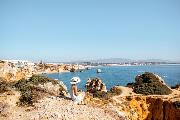 Woman enjoying great view on the rocky coastline during the sunrise in Lagos on the south of Portugal