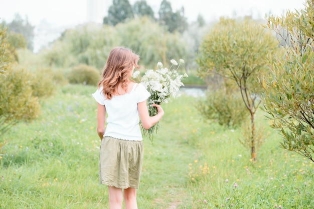 Photo woman enjoying the life in the field with flowers. nature beauty, blue cloudy sky and colorful field with flowers.