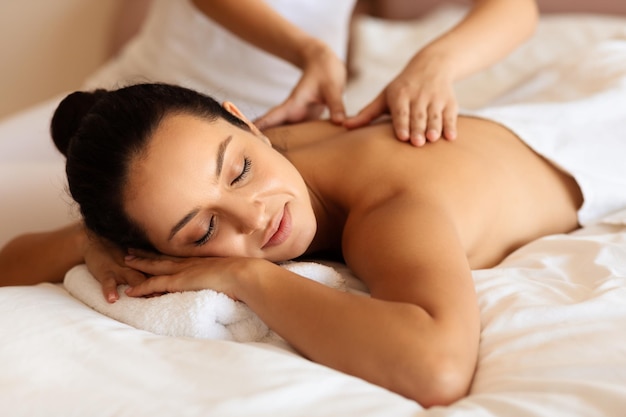 Woman enjoying massage and calming touch of masseuses hands indoor