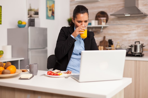 Woman enjoying an orange juice in the morning during a video conference