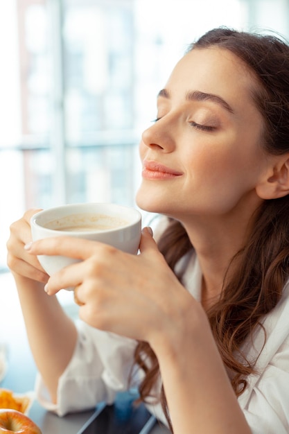 Woman enjoying the smell of freshly brewed coffee