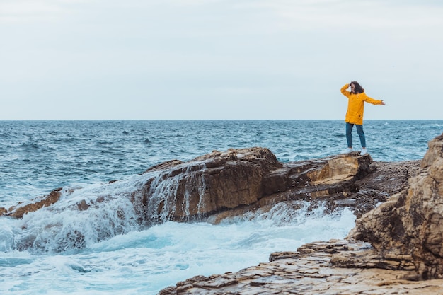 Woman enjoying storm weather at sea rocky seaside