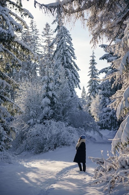 雪のおとぎ話の森の自然の中で晴れた日を楽しんでいる女性