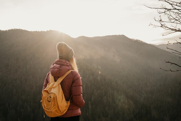 Woman enjoying the sunset in nature on the edge of a rock cliff Woman hiker enjoys mountains view