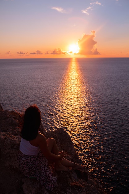 海に沈む夕日を楽しむ女性