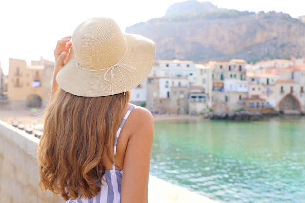 Woman enjoying view of Cefalu old town in Sicily, Italy