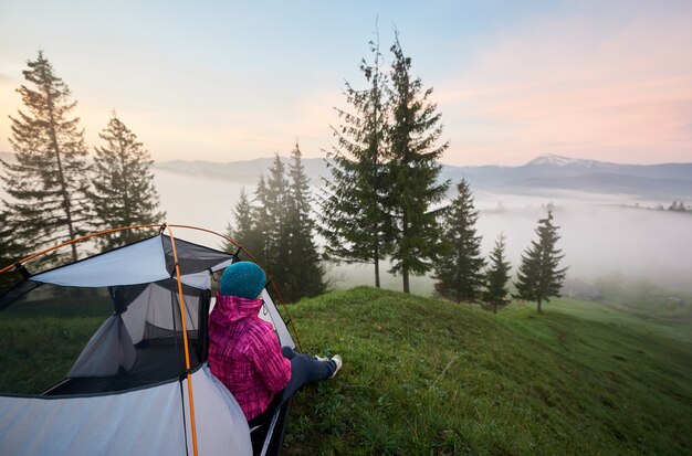 Woman enjoying view of small village in valley covered with dense fog