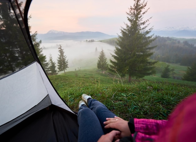 Woman enjoying view of small village in valley covered with dense fog