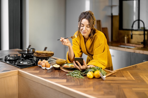 Woman enjoys breakfast on the kitchen in the morning