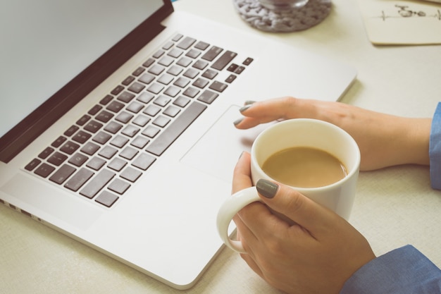 Woman enjoys a laptop and drinks coffee