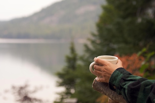 Женщина наслаждается утренним кофе на берегу озера