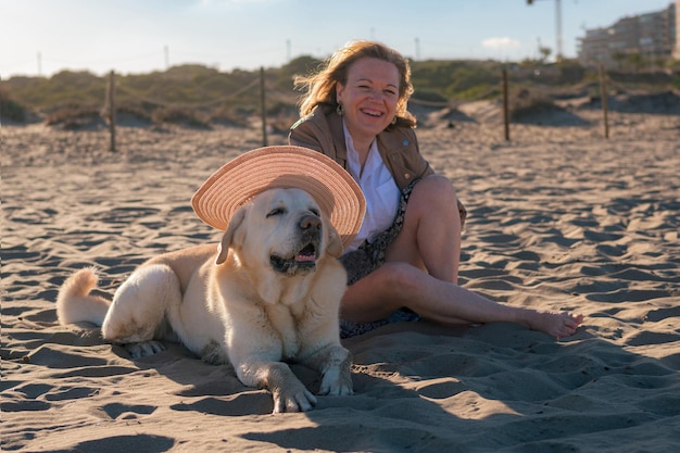 ビーチで犬に帽子をかぶせて楽しむ女性