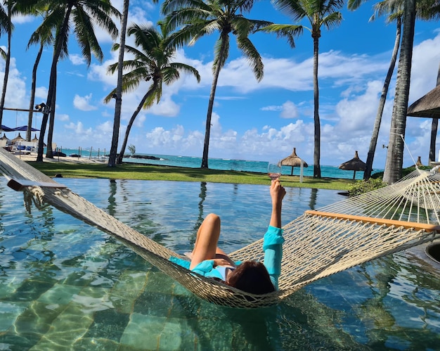 Woman enjoys wine in hammock by sea or ocean