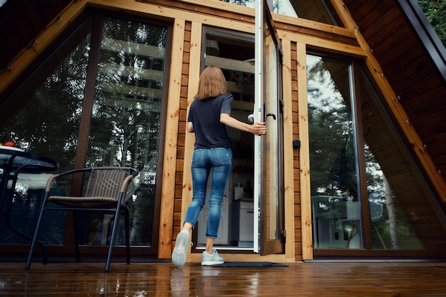 Woman enters forest cabin back view