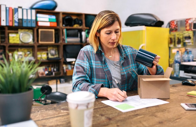 Photo woman entrepreneur checking return form of wrong package sent to client in online shop