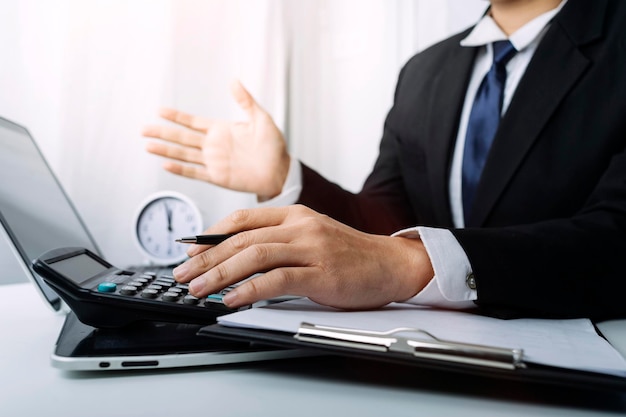 Woman entrepreneur using a calculator with a pen in her hand calculating financial expense at home office