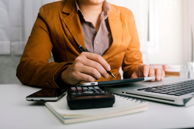 Imprenditrice donna che utilizza una calcolatrice con una penna in mano per calcolare le spese finanziarie a casa