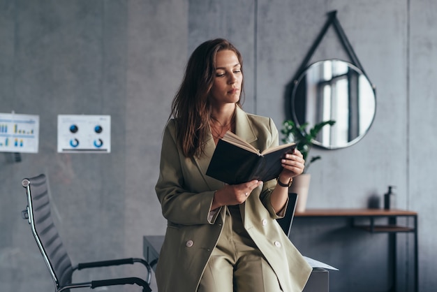 Photo woman entrepreneur at work reading notes in a planner.