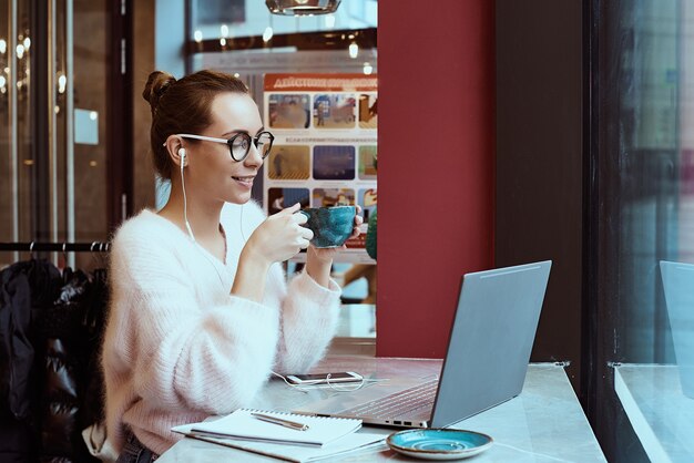 Женщина-предприниматель работает из кафе и разговаривает по мобильному телефону