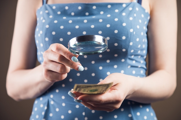 Фото Женщина рассматривает деньги с лупой. концепция проверки подделки