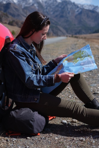 Woman examining map while sitting near the car