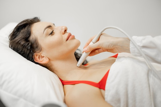 Woman examining thyroid gland with ultrasound